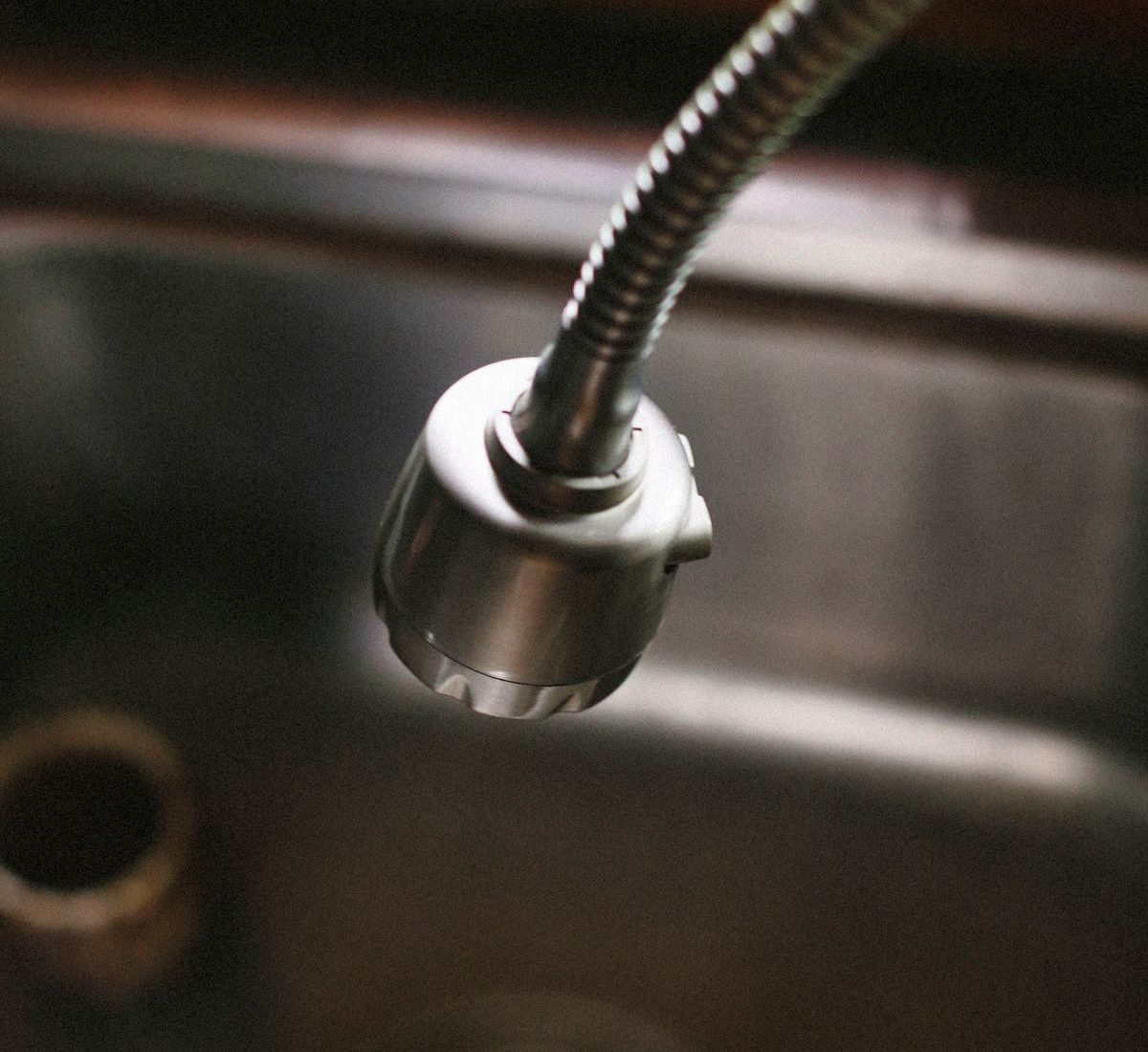 Pull-out kitchen faucet head extended on its hose, showing the compact spout geometry