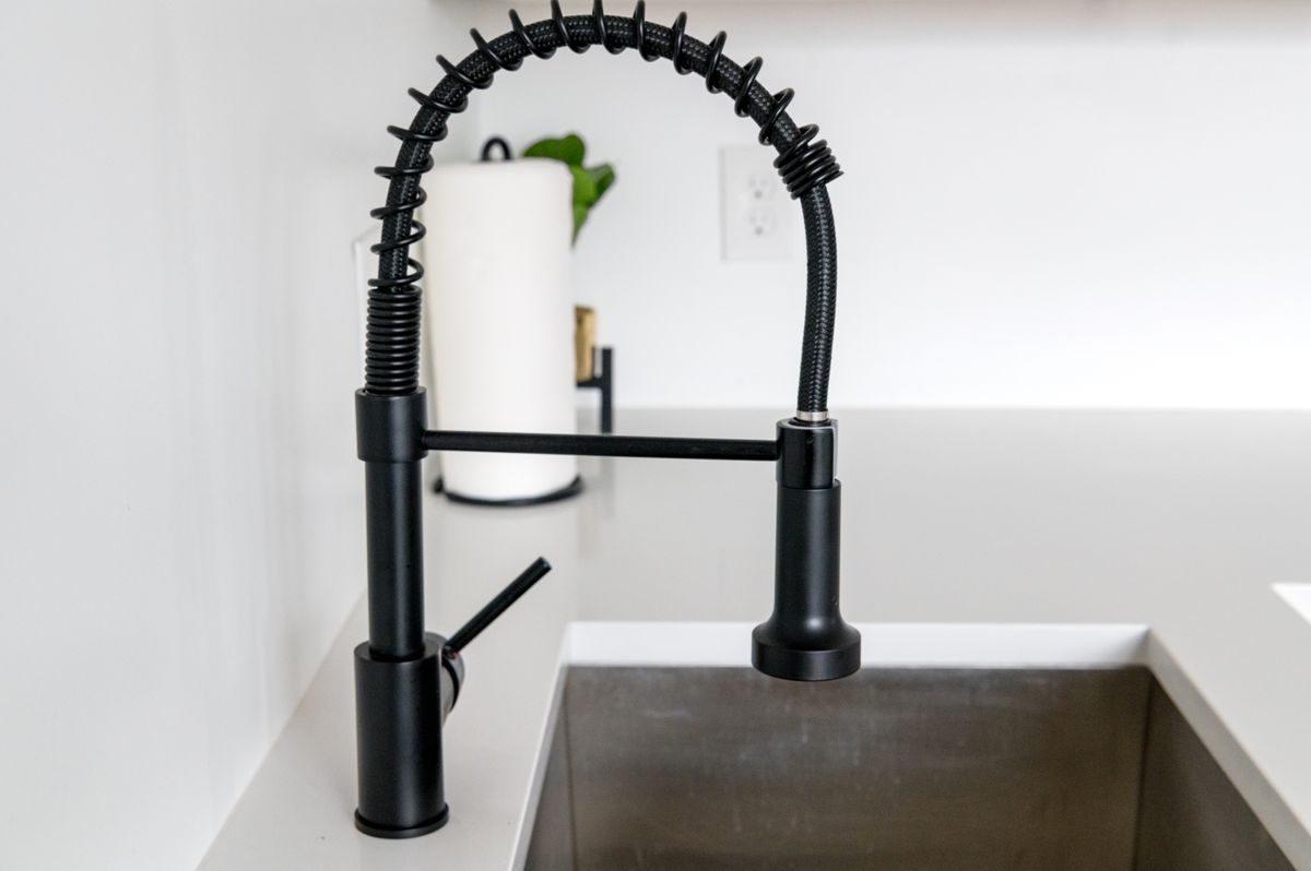 Commercial-style pre-rinse kitchen faucet with an exposed spring coil over the sink